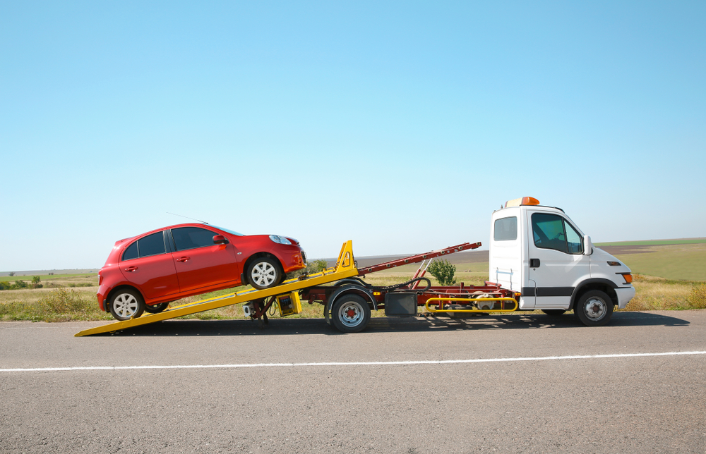 red car being pulled onto flat bed truck